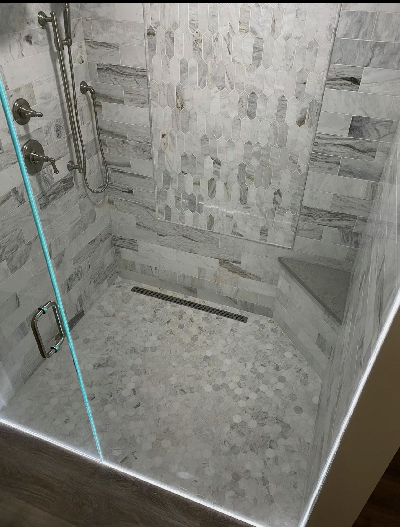 Glass shower enclosure with patterned stone tile